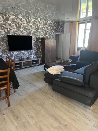 un salon avec un canapé et une télévision à écran plat dans l'établissement Maison avec cour, à Neuvy-sur-Barangeon