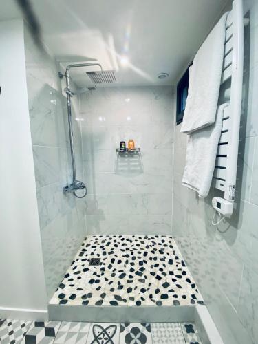 La salle de bains est pourvue d'une douche et d'un sol noir et blanc. dans l'établissement Ici, dort un Gorille, à Planay