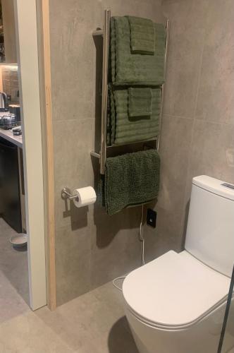 a bathroom with a white toilet and green towels at THE BIRD'S NEST - Secluded getaway! in Christchurch
