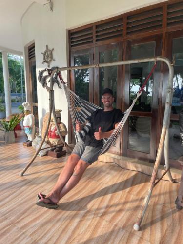 a man sitting in a hammock in a room at Suzukis lagoon front in Katunayake