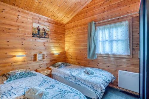 sypialnia z dwoma łóżkami w chacie z bali w obiekcie Chalet 17 tournesol Mauroux w mieście Mauroux
