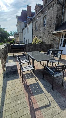 a picnic table and benches in front of a building at La Bonnerie, Le Cabinet des lettres 3 chambres in La Bouexière