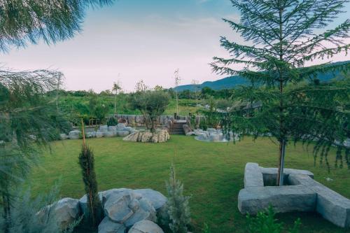 a garden with trees and rocks in a field at Khaoyai Art Tree in Pong Talong