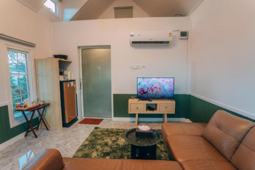 a living room with a couch and a flat screen tv at Khaoyai Art Tree in Pong Talong