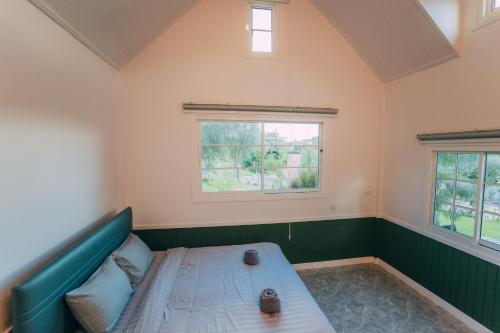 a small room with a bed and two windows at Khaoyai Art Tree in Pong Talong