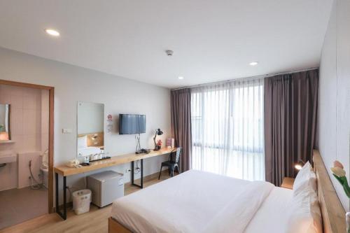 a bedroom with a bed and a desk and a window at Esy Hotel in Lamphun