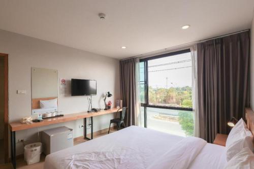 a bedroom with a bed and a desk and a window at Esy Hotel in Lamphun