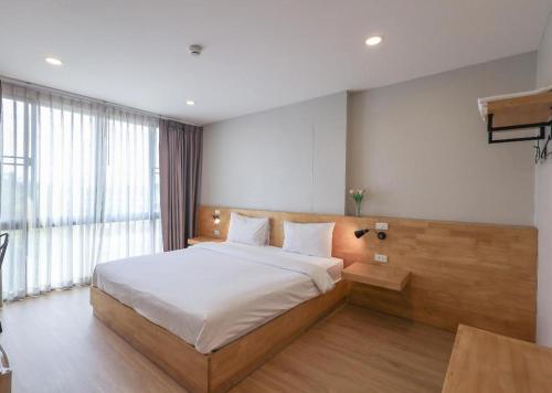 a bedroom with a bed and a large window at Esy Hotel in Lamphun
