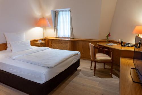 a hotel room with a bed and a desk at Waldhaus Reinbek in Reinbek