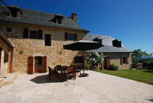 une table avec un parasol devant un bâtiment dans l'établissement Les Charmes de Grèzes- location de samedi à samedi, à Grèzes
