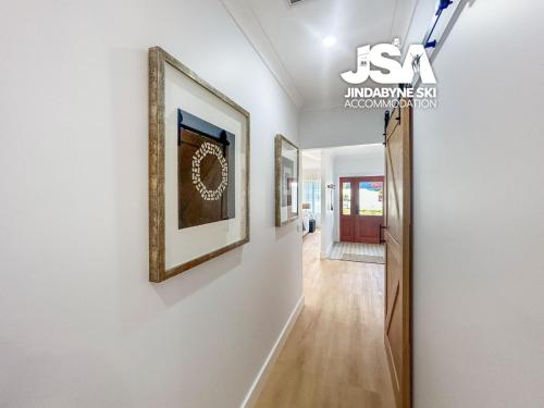 a hallway with paintings on the wall and a hallway with a door at Allenvale in Jindabyne