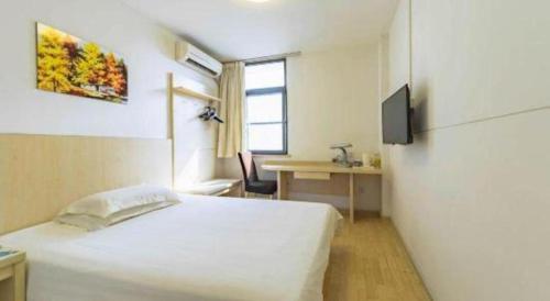 a bedroom with a large white bed and a desk at Magnotel Shanghai Henglong Plaza in Shanghai