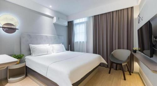 a hotel room with a white bed and a chair at Magnotel Shanghai Henglong Plaza in Shanghai