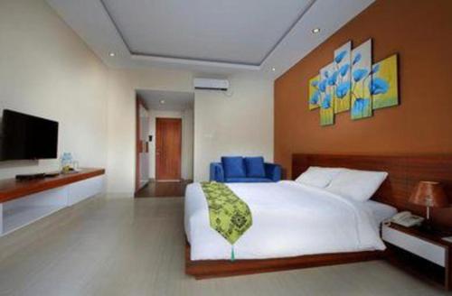 a bedroom with a white bed and a television at Umah Bali Suites in Denpasar