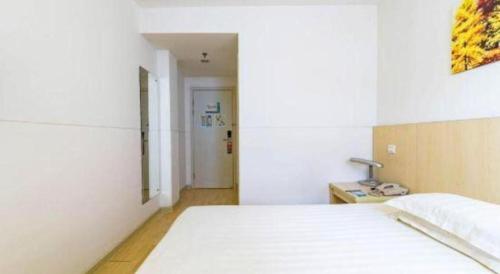 a bedroom with a white bed and a lamp on a table at Magnotel Shanghai Henglong Plaza in Shanghai
