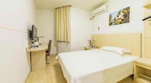 a bedroom with a bed and a desk and a television at Magnotel Shanghai Henglong Plaza in Shanghai