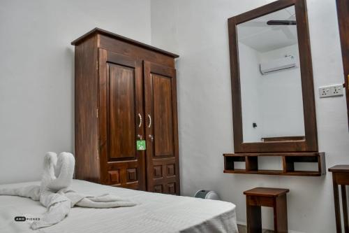 a bedroom with a bed with a mirror and a dresser at Coconut Resort Arugambay in Arugam Bay