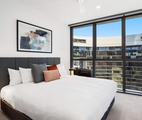 a bedroom with a large bed and large windows at Queen's Wharf Residences Official in Brisbane