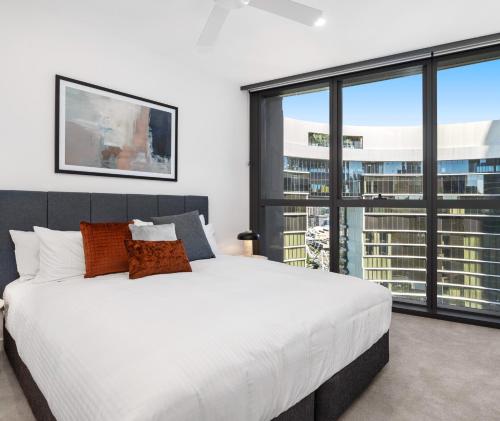 a bedroom with a large white bed and large windows at Queen's Wharf Residences Official in Brisbane