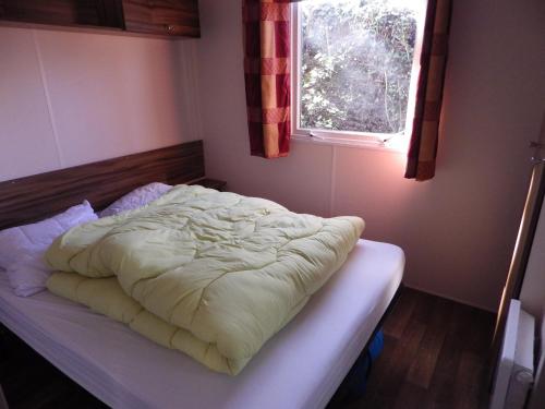 an unmade bed in a bedroom with a window at Mobil Home in Saint-Jean-de-Monts