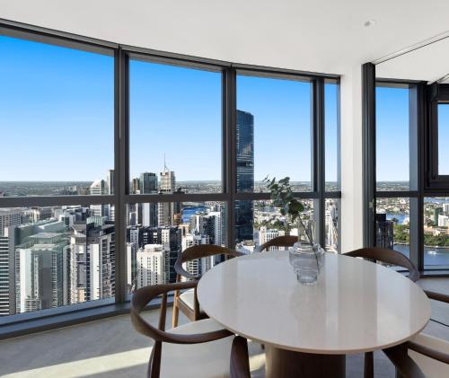 a white table and chairs in a room with windows at Queen's Wharf Residences Official in Brisbane