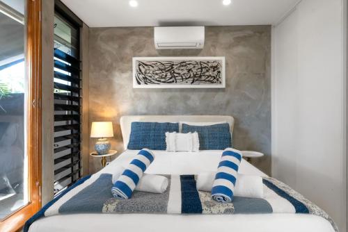 a bedroom with a bed with blue and white pillows at Belle Escapes Villa Riviera in Palm Cove
