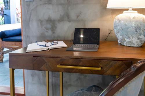 a laptop on a desk with a lamp and a book at Belle Escapes Villa Riviera in Palm Cove