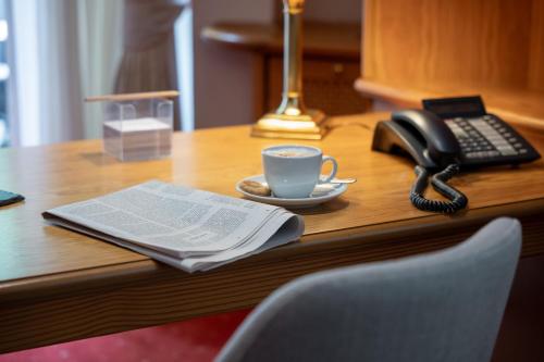 a telephone and a cup of coffee on a desk at Waldhaus Reinbek in Reinbek