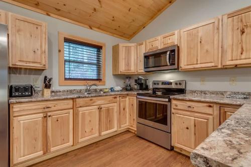 a kitchen with wooden cabinets and stainless steel appliances at High Johnny's Hideout- Secluded w Private Hot Tub in Sevierville