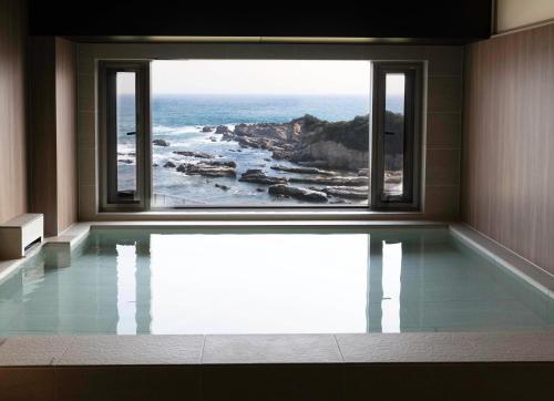 a room with a swimming pool with a view of the ocean at Shiosai Resort Kamogawa in Kamogawa