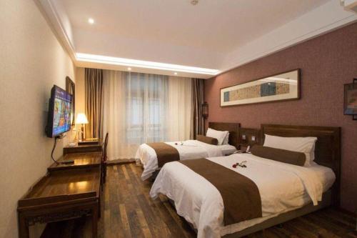 a hotel room with two beds and a flat screen tv at James Joyce Coffetel Xian Dayanta Metro Station Branch in Xi'an