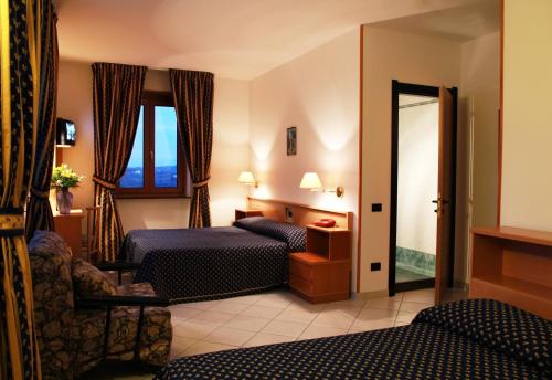 Habitación de hotel con 2 camas y ventana en Hotel Lo Smeraldo, en Cisternino