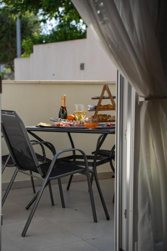 a table with chairs and wine bottles on a patio at Pool and Breakfast Apartments Villa Maro in Novalja
