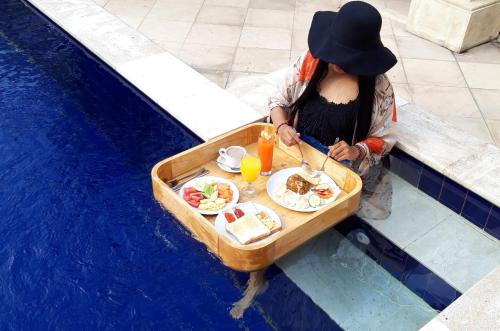a woman sitting in a boat with a tray of food at Grand Raka Homestay in Lovina