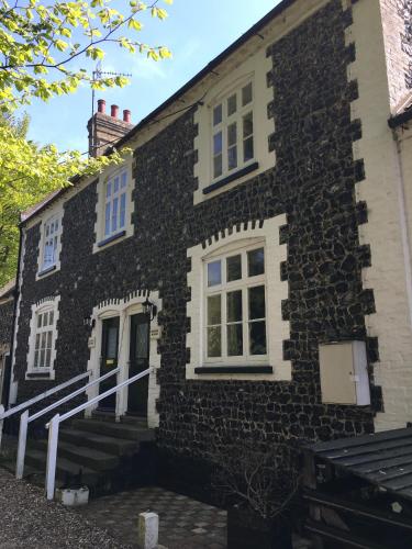 a stone house with white windows and stairs on it at The Crown Hotel in Mundford