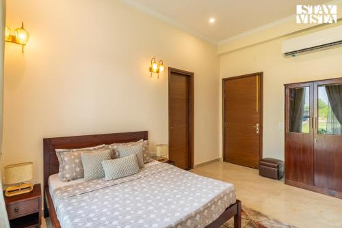 a bedroom with a bed with a wooden headboard at StayVista at The Mira House with Pool, WiFi in Sohna