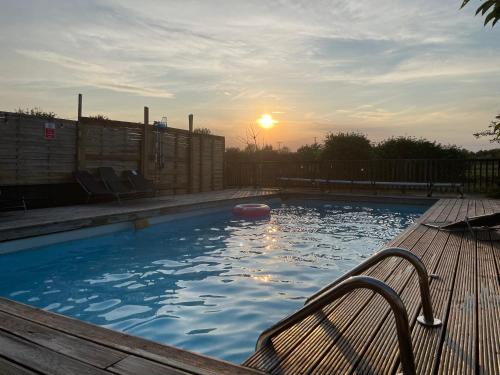 a swimming pool with a bench and the sunset at Spacious Cabin with Private Hot Tub, and Private Pool, in 5 Acres - intimate Special stay For 2 Adults - plus 1 child under 2 and up to 2 dogs stay for free in Downham
