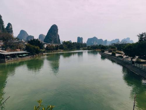 a river with mountains in the background and a bridge at Yangshuo CheerMay Hotel in Yangshuo