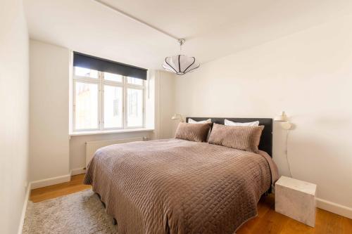 a white bedroom with a bed and a window at Perfect 3 bedroom apartment in the heart of CPH in Copenhagen