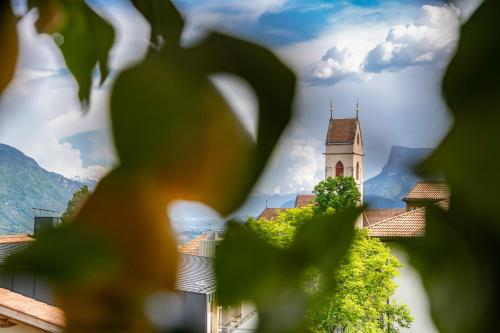a church seen through the leaves of a tree at Eco Bnb & Apartments Bründlerhof in Marlengo