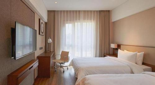 a hotel room with two beds and a flat screen tv at NH Shijiazhuang Financial Center in Shijiazhuang
