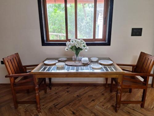 a dining room table with a vase of flowers on it at Cozy Scenic Farmhouse Retreat in Mangalore