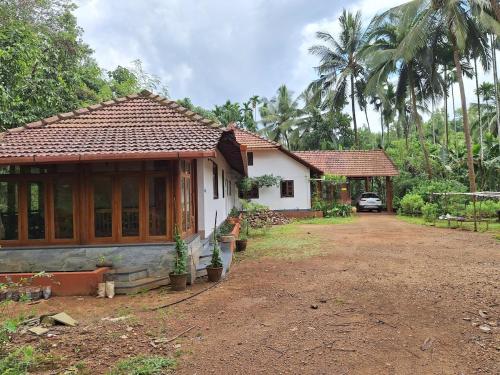 a house with a car parked in front of it at Cozy Scenic Farmhouse Retreat in Mangalore