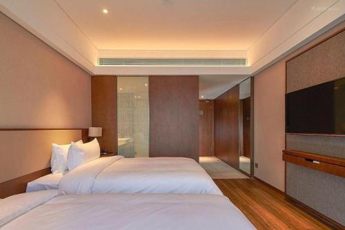 a hotel room with two beds and a flat screen tv at NH Shijiazhuang Financial Center in Shijiazhuang