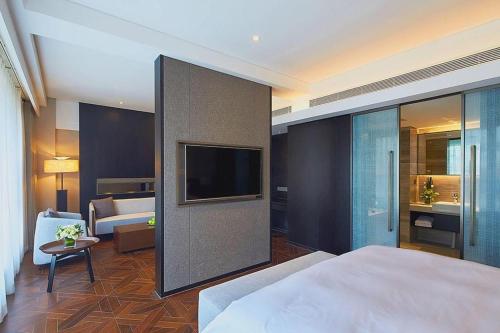 a hotel room with a bed and a tv and a bedroom at NH Shijiazhuang Financial Center in Shijiazhuang