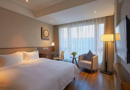 a hotel room with a large bed and a chair at NH Shijiazhuang Financial Center in Shijiazhuang