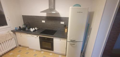 Il comprend une cuisine équipée d'un réfrigérateur blanc et d'une cuisinière. dans l'établissement Maison individuelle calme, à Mer