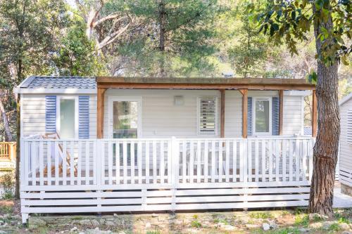 a small house with a white fence and a tree at Mobile homes Pine Sea Banjole in Banjole