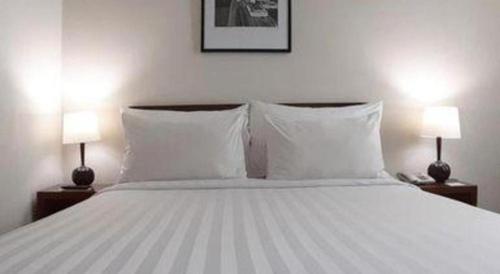 a bedroom with a white bed with two lamps at PARK HOTEL Cawang Jakarta in Jakarta