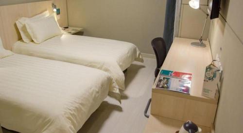 a small room with two beds and a mirror at Magnotel Shanghai Maglev Station in Shanghai